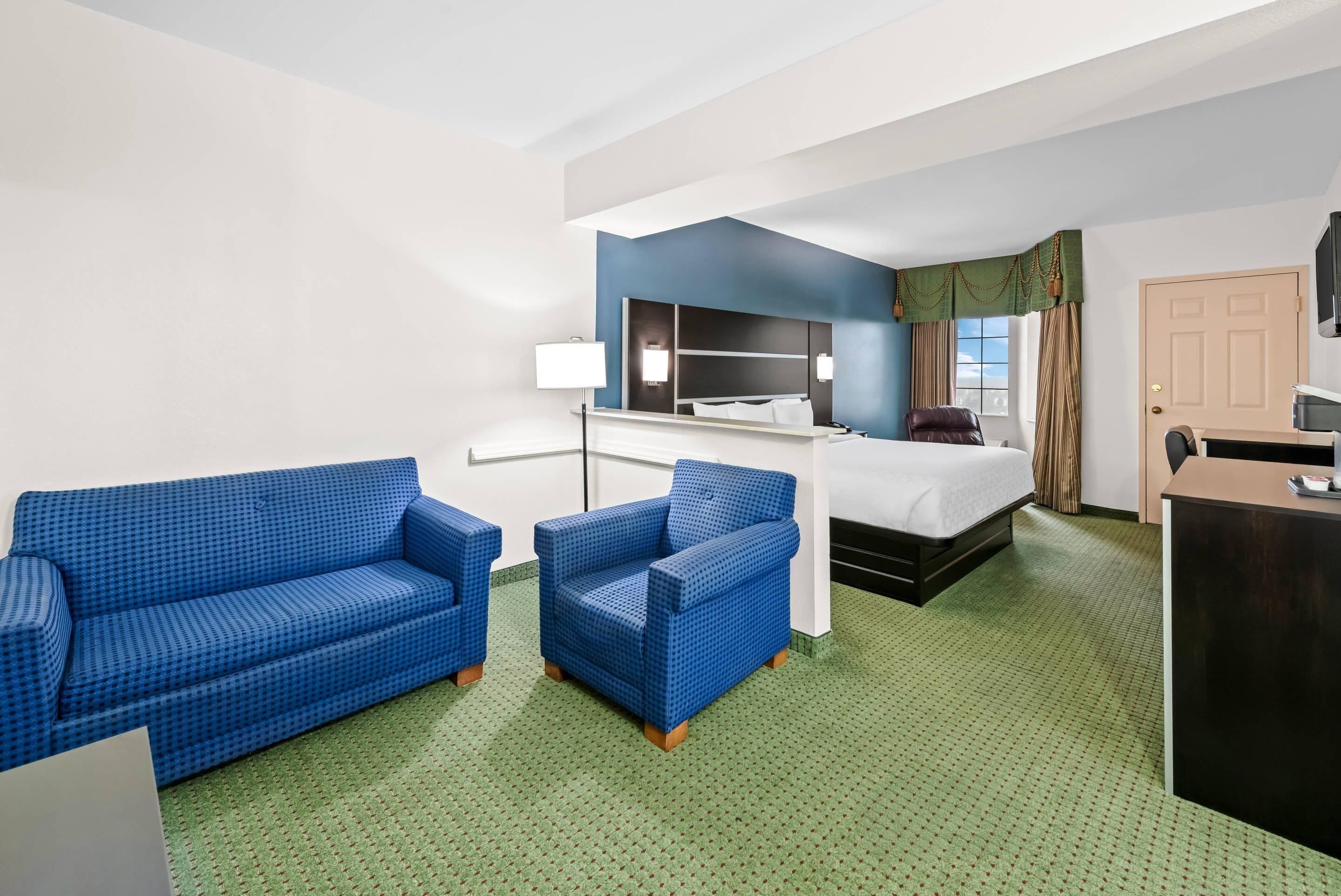 Een hotelkamer met een bed, een blauwe bank, een stoel, een bureau en een televisie.