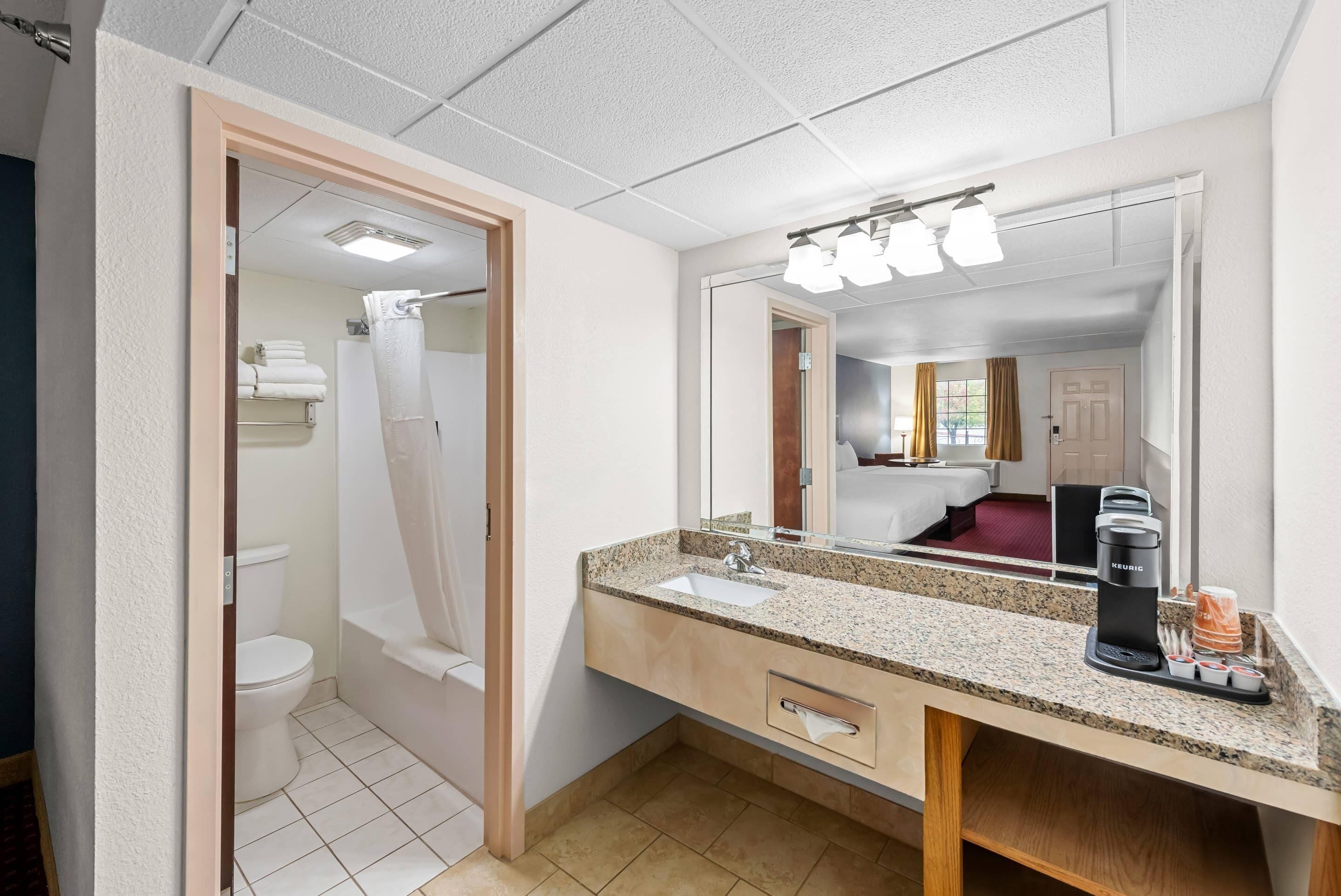 A bathroom with a sink, mirror, and shower.