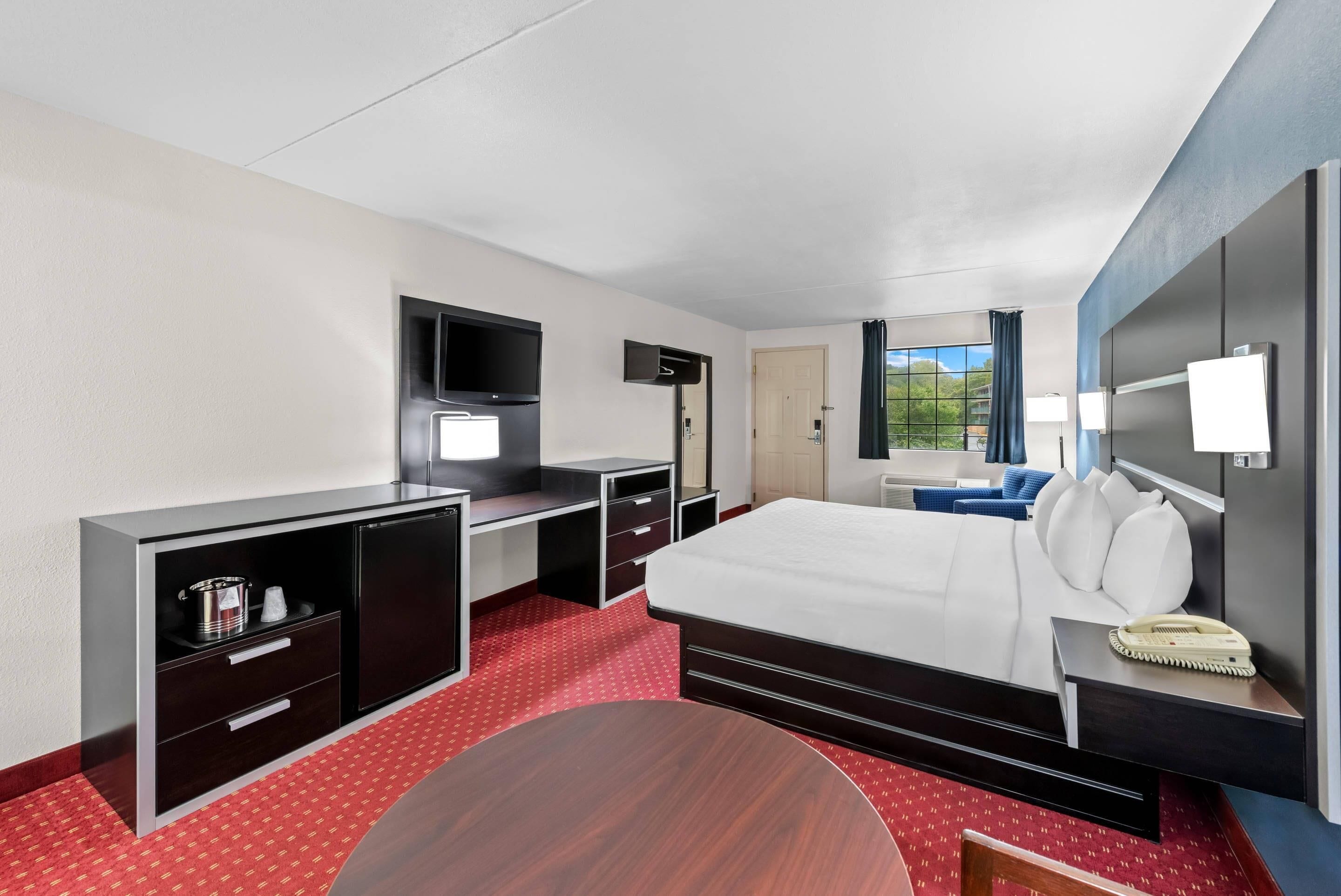 Ein Hotelzimmer mit Bett, Schreibtisch, Stuhl, Fernseher und einem Fenster mit Aussicht.