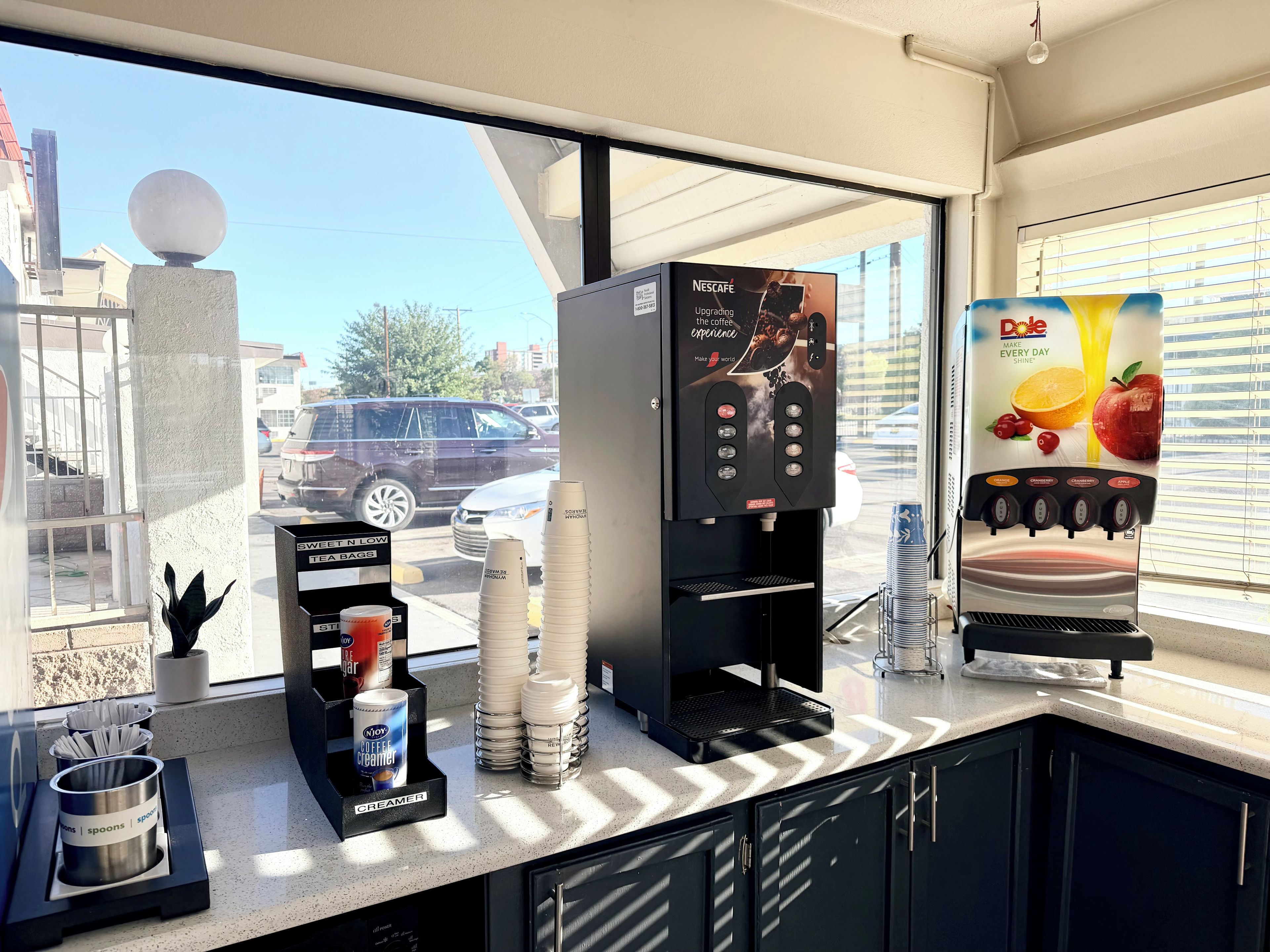 Une machine à café avec une publicité pour Nescafe, un distributeur de crème et un distributeur de jus de fruits Dole.