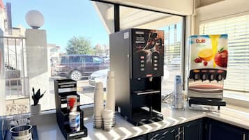 Una cafetera con publicidad de Nescafé, un dispensador de crema y un dispensador de jugo Dole.