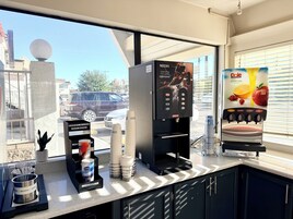 Una cafetera con publicidad de Nescafé, un dispensador de crema y un dispensador de jugo Dole.