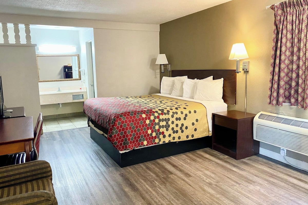 Ett hotellrum med en säng, sänglampor, ett skrivbord och ett fönster.