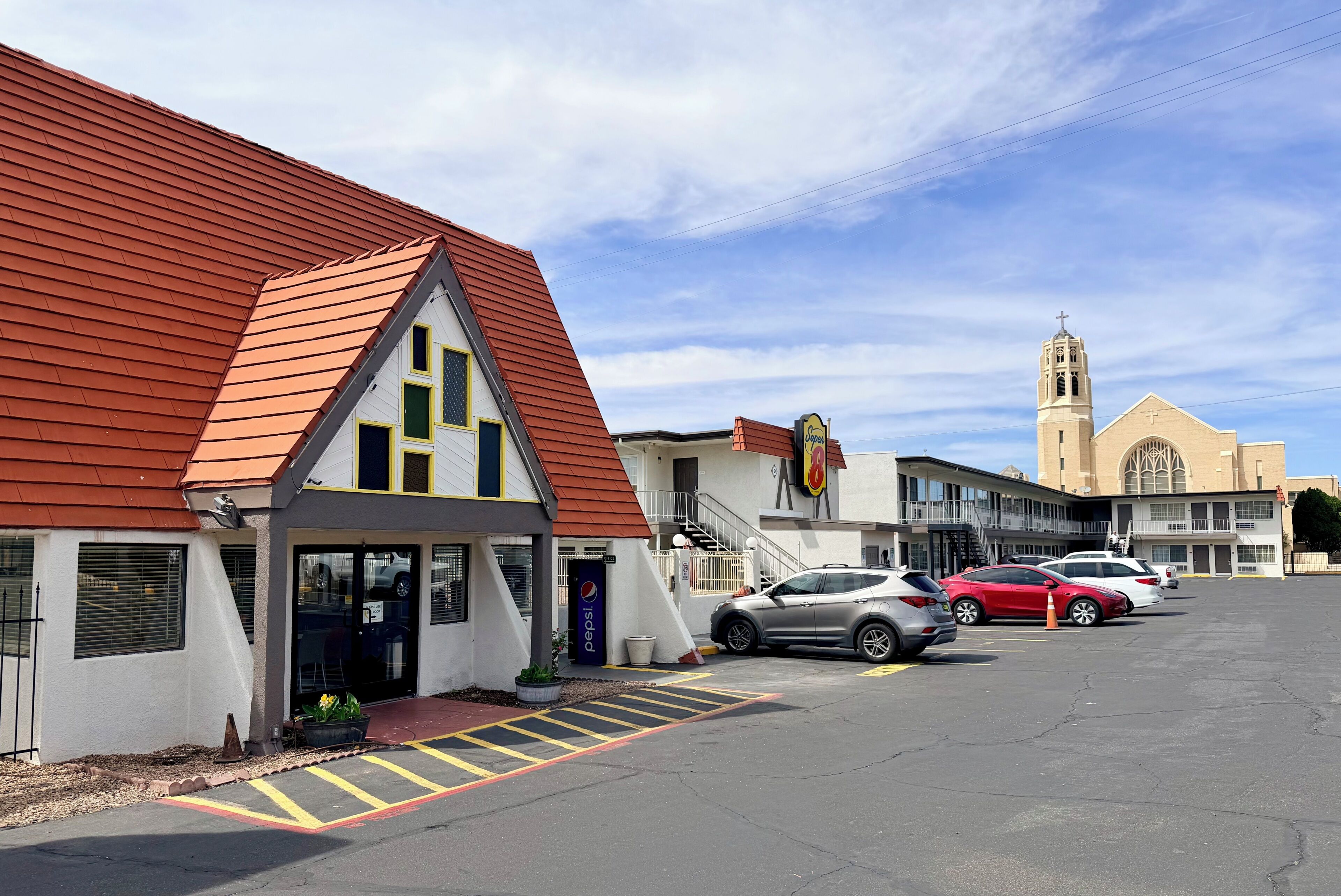A building with a red roof, a Pepsi sign, and a parking lot with cars.
