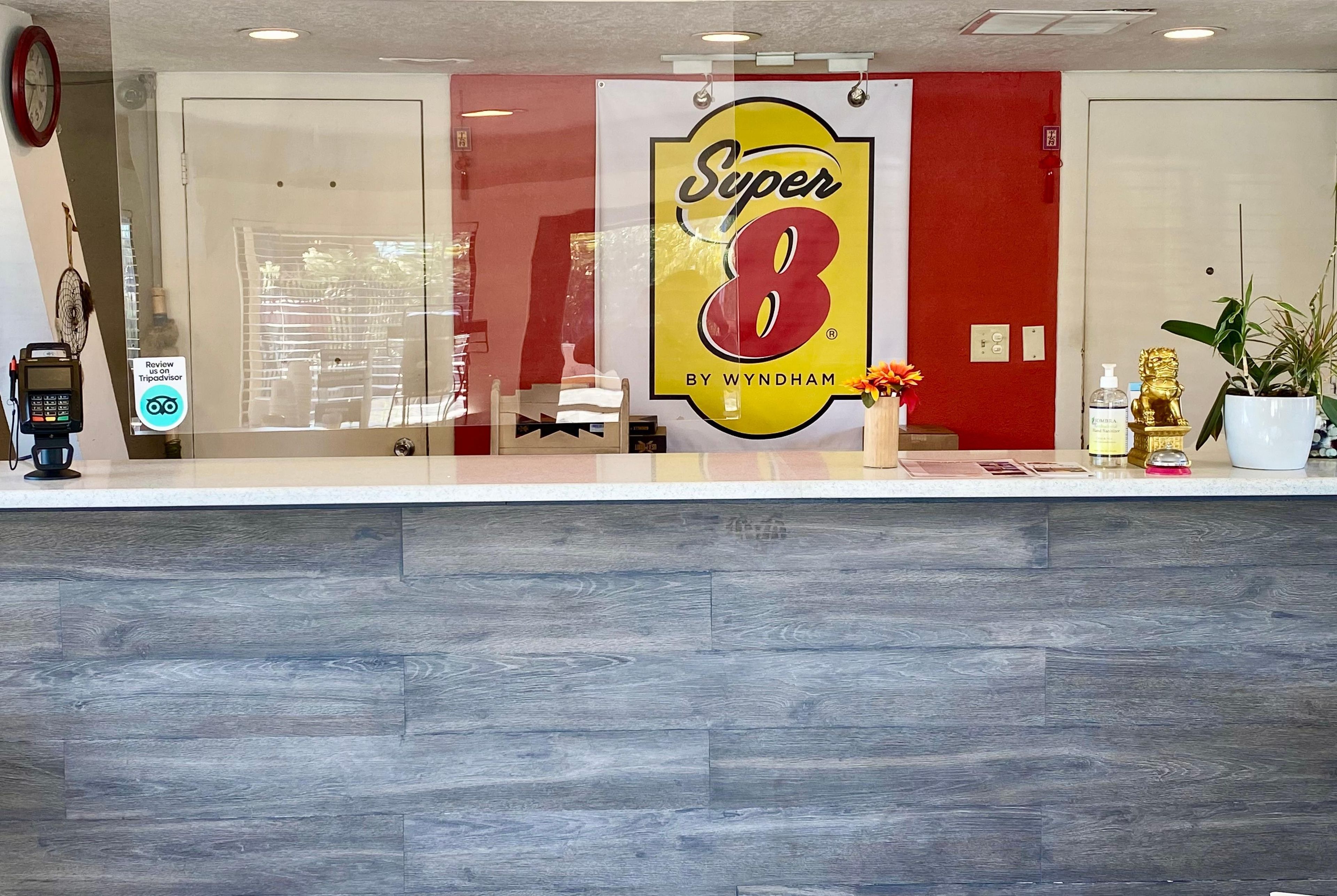 A reception desk with a large 'Super 8' sign, a clock, a plant, and a water dispenser.