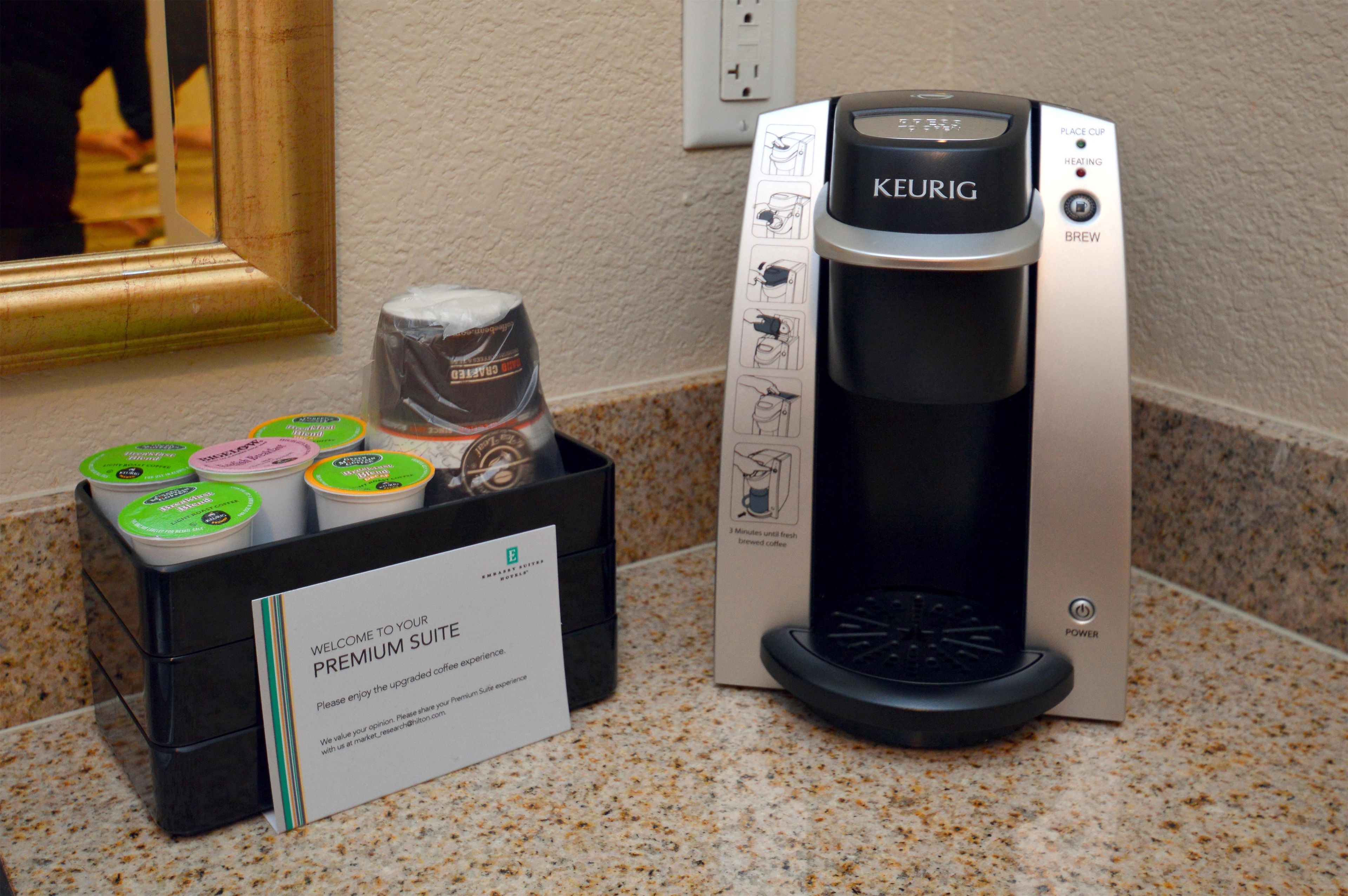 A Keurig coffee machine with a 'Welcome to your Premium Suite' sign, a coffee pod holder, and a power button.