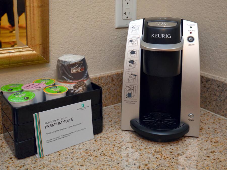 A Keurig coffee machine with a 'Welcome to your Premium Suite' sign, a coffee pod holder, and a power button.