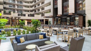 A modern hotel lobby with a central seating area, multiple floors, and a bar/lounge area.