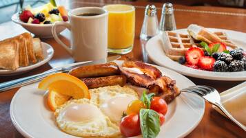 A breakfast plate with eggs, bacon, tomatoes, and a slice of orange.