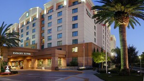 A multi-story hotel with 'EMBASSY SUITES' signage, a parking lot, and palm trees.