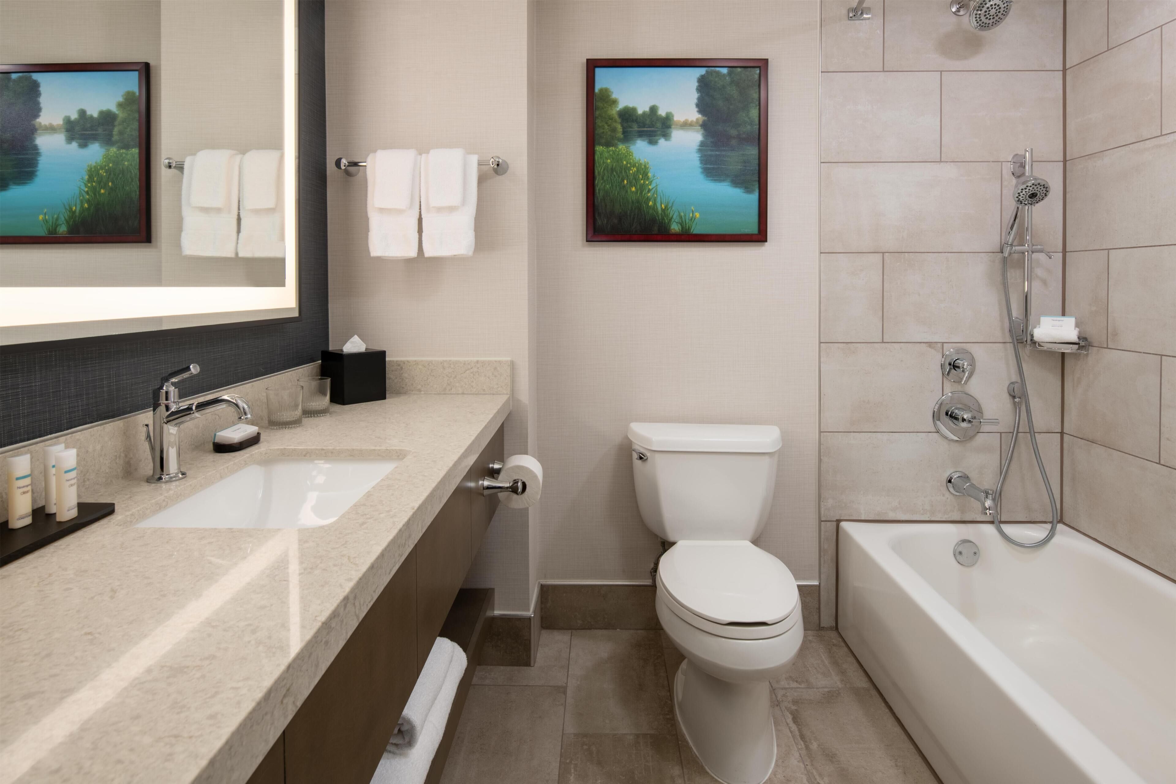 Une salle de bain équipée d’un lavabo, de toilettes, d’une baignoire et de deux tableaux encadrés accrochés aux murs.