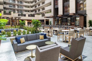 Relax in a serene outdoor lounge surrounded by lush greenery and comfortable seating options.
