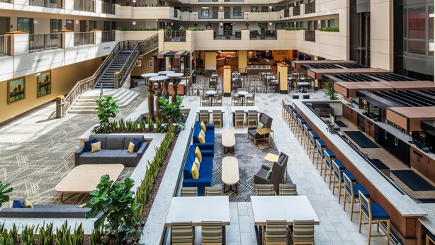 A multi-level atrium with outdoor seating, a central staircase, and a bar area.