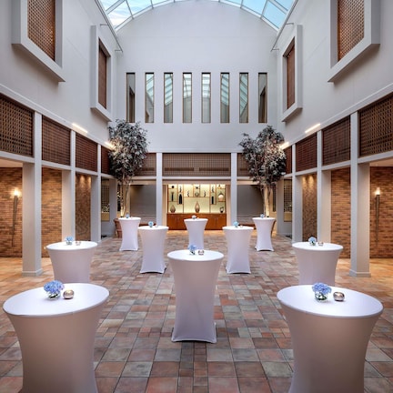 A spacious atrium with high ceilings, multiple tables, and potted plants.