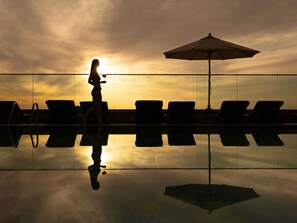 A person walking by a pool with lounge chairs and an umbrella. - Fairmont Dubai (Dubai)