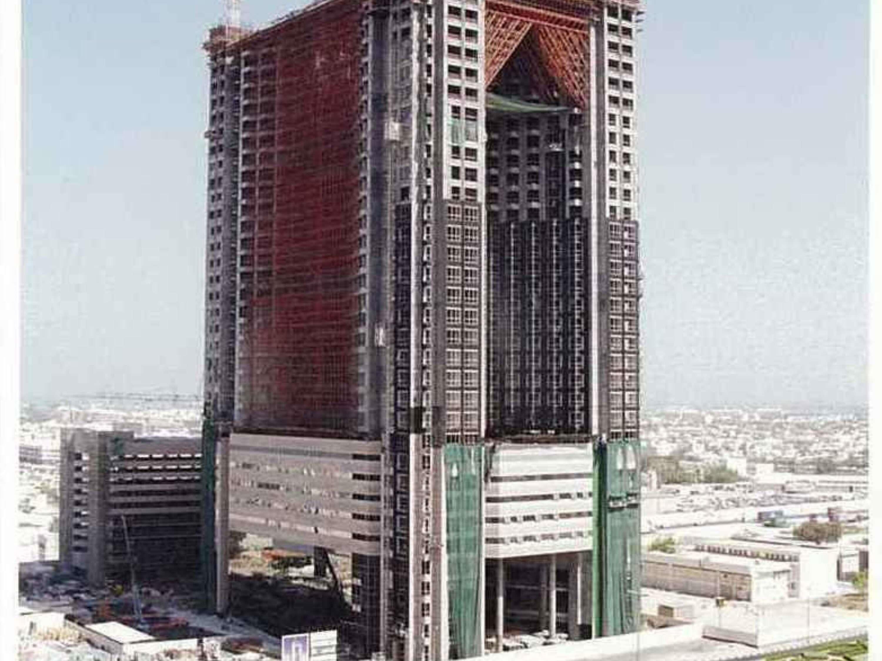 A high-rise building under construction with multiple floors, a central core, and a flat roof.