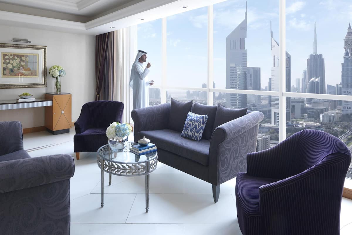Ein modernes Wohnzimmer mit Blick auf die Stadt, inklusive Sofa, Sesseln, einem Glastisch und einer dekorativen Vase.