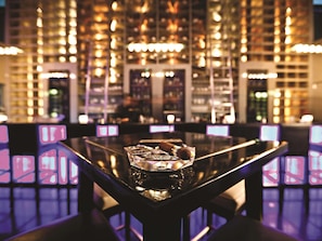 A bar area with a polished table, a bottle, and a bar counter.