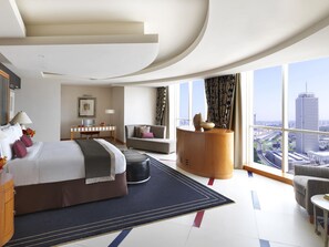 A modern hotel room with a large bed, a desk, a sofa, and a view of the cityscape. - Fairmont Dubai (Dubai)