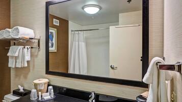 Un baño moderno con un espejo grande, un lavabo negro y un perchero con toallas dobladas.