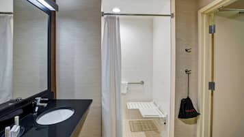 Un baño moderno con lavamanos negro, espejo y cortina de ducha blanca.