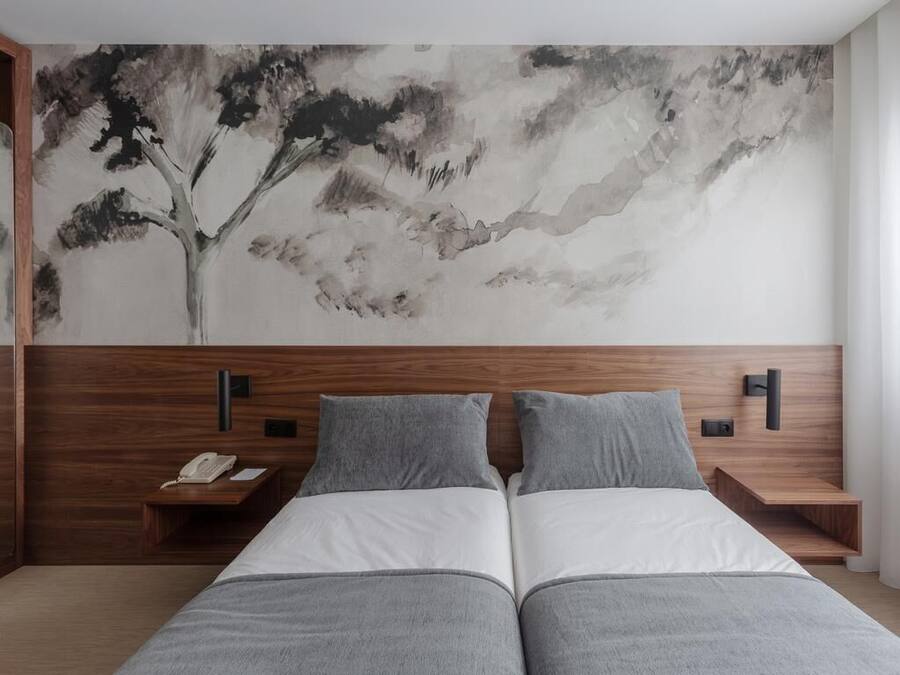 Un dormitorio moderno con una cama grande, dos mesitas de noche y un teléfono instalado en la pared.