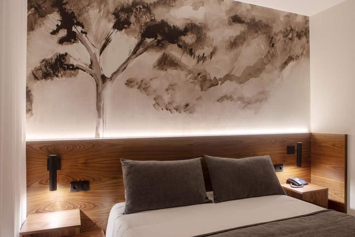 Un dormitorio moderno con una cama grande, dos mesitas de noche y una lámpara de pared.