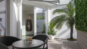 A balcony with wicker furniture, a glass table, and a potted plant. - Hotel Afonso V (Aveiro)