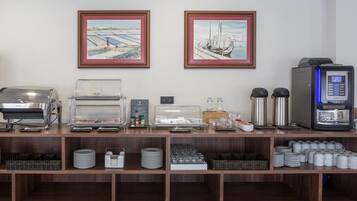 Een buffetopstelling met een koffieapparaat, een broodrooster en een magnetron. Er hangen twee ingelijste foto's aan de muur.