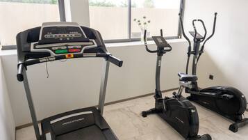 Un gimnasio en casa con una cinta de correr ProForm, una elíptica y una bicicleta estática.