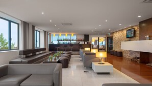 A modern lobby with seating areas, a bar, and a television screen. - Hotel dos Zimbros (Sesimbra)