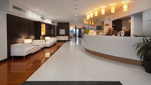 A modern hotel lobby with a reception desk, seating area, and artwork on the walls. - Hotel dos Zimbros (Sesimbra)