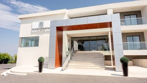 A modern hotel entrance with a staircase leading to the lobby, large windows, and a clear sky. - Hotel dos Zimbros (Sesimbra)