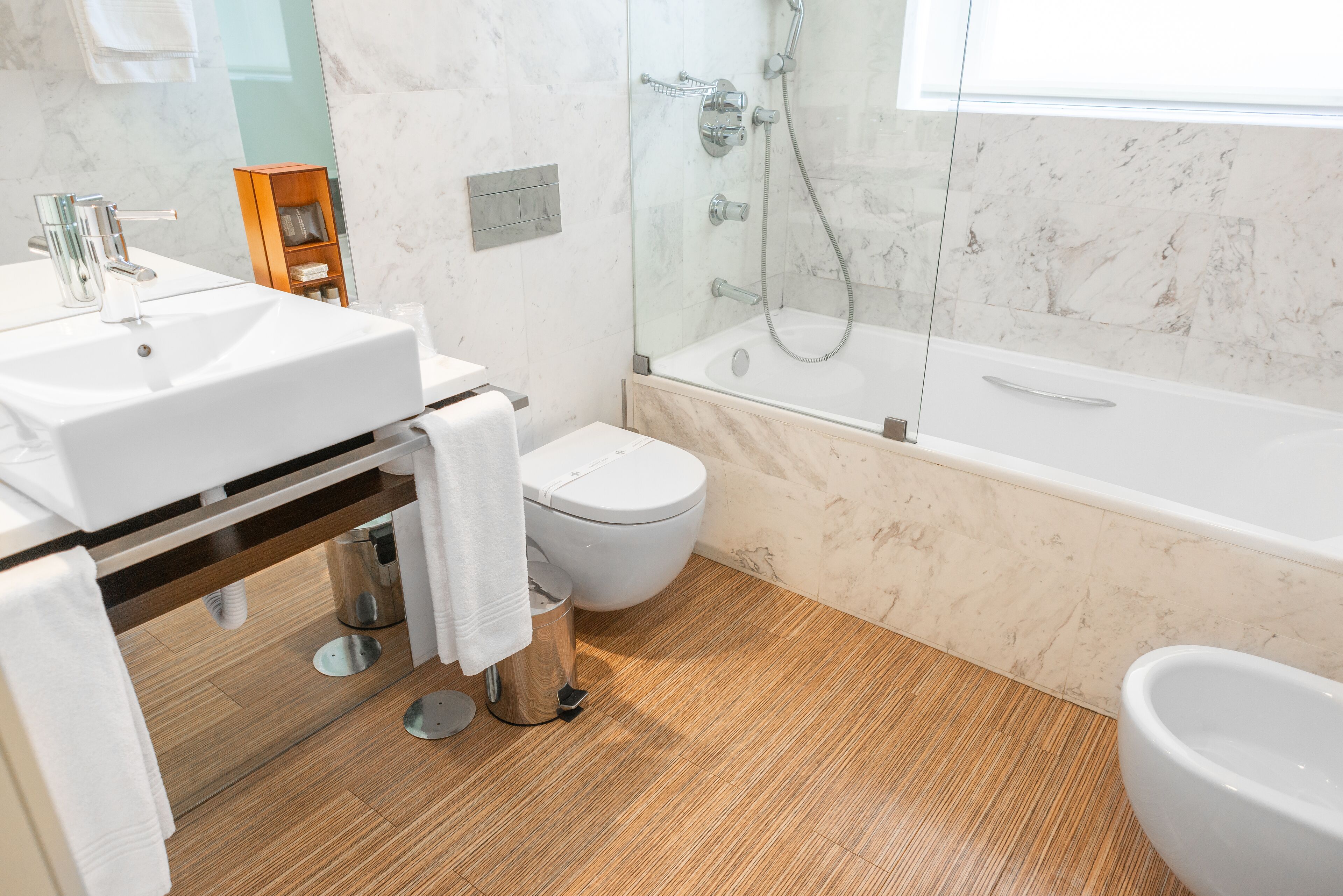 Un baño moderno con lavamanos, inodoro y bañera blancos.