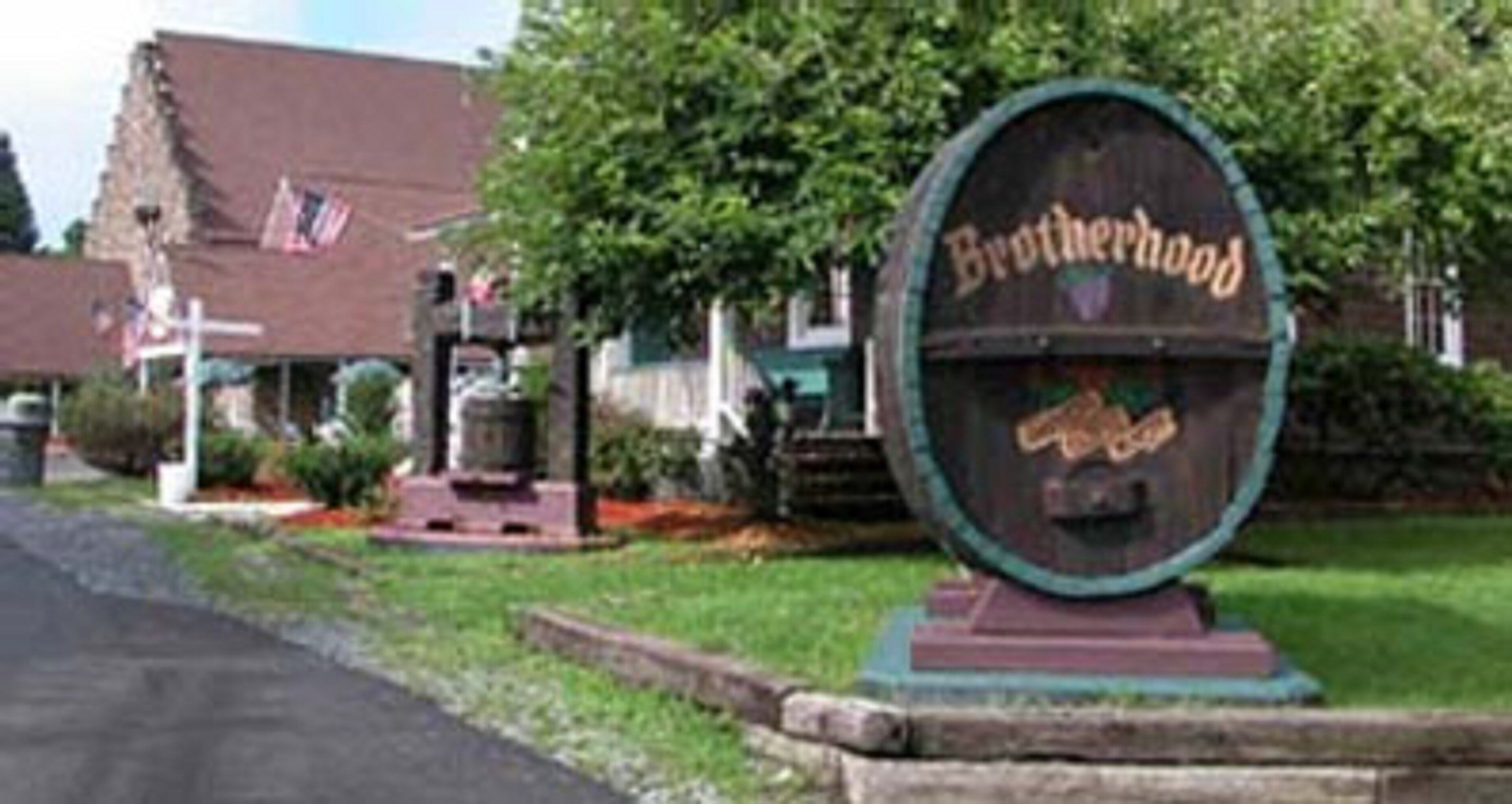 A wooden barrel-shaped sign with the name 'Brotherhood' and a small plaque below it.