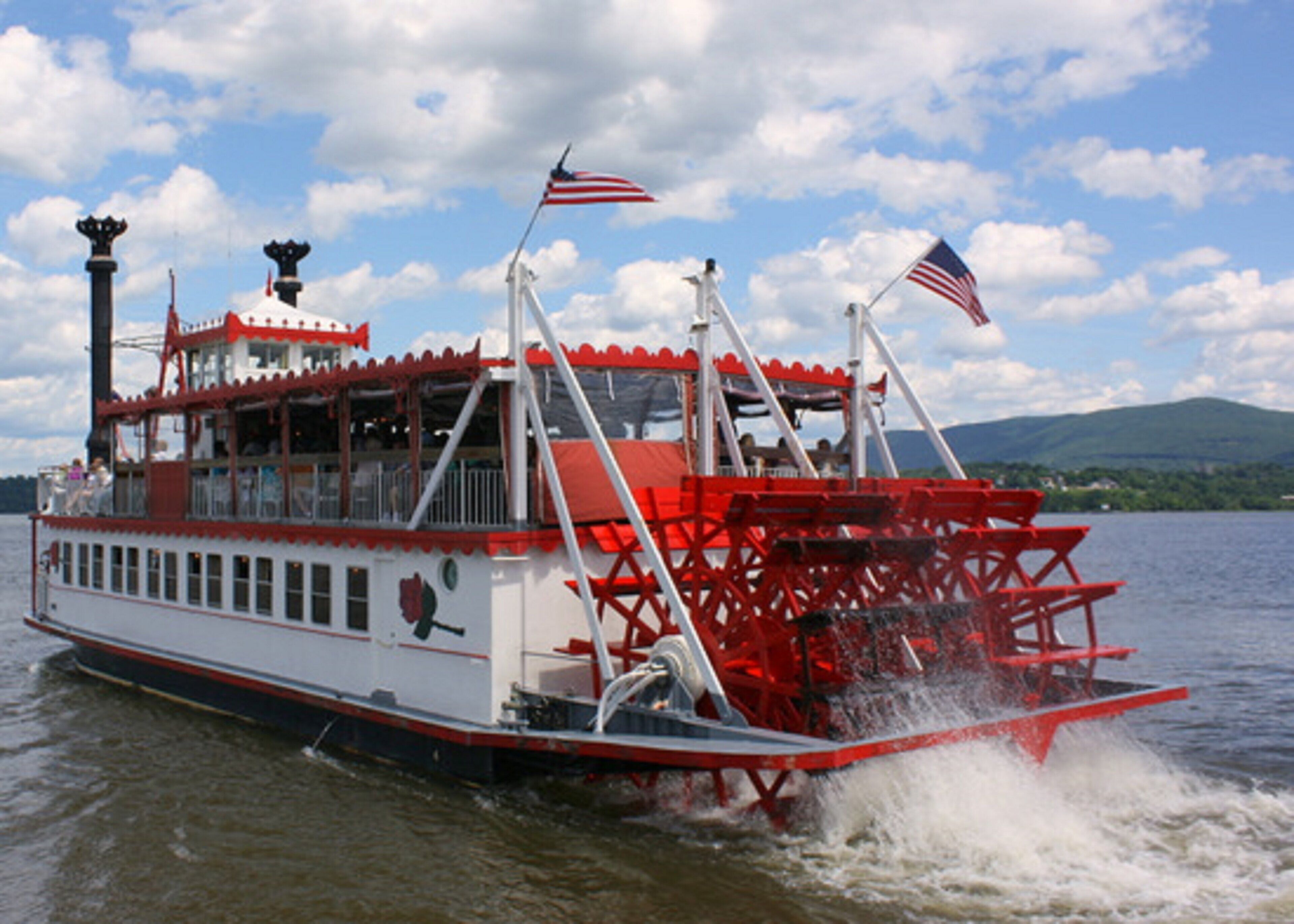 Un barco de vapor con exterior rojo y blanco, varias cubiertas y banderas estadounidenses.