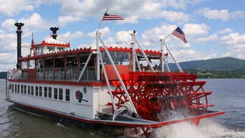 Un barco de vapor con exterior rojo y blanco, varias cubiertas y banderas estadounidenses.