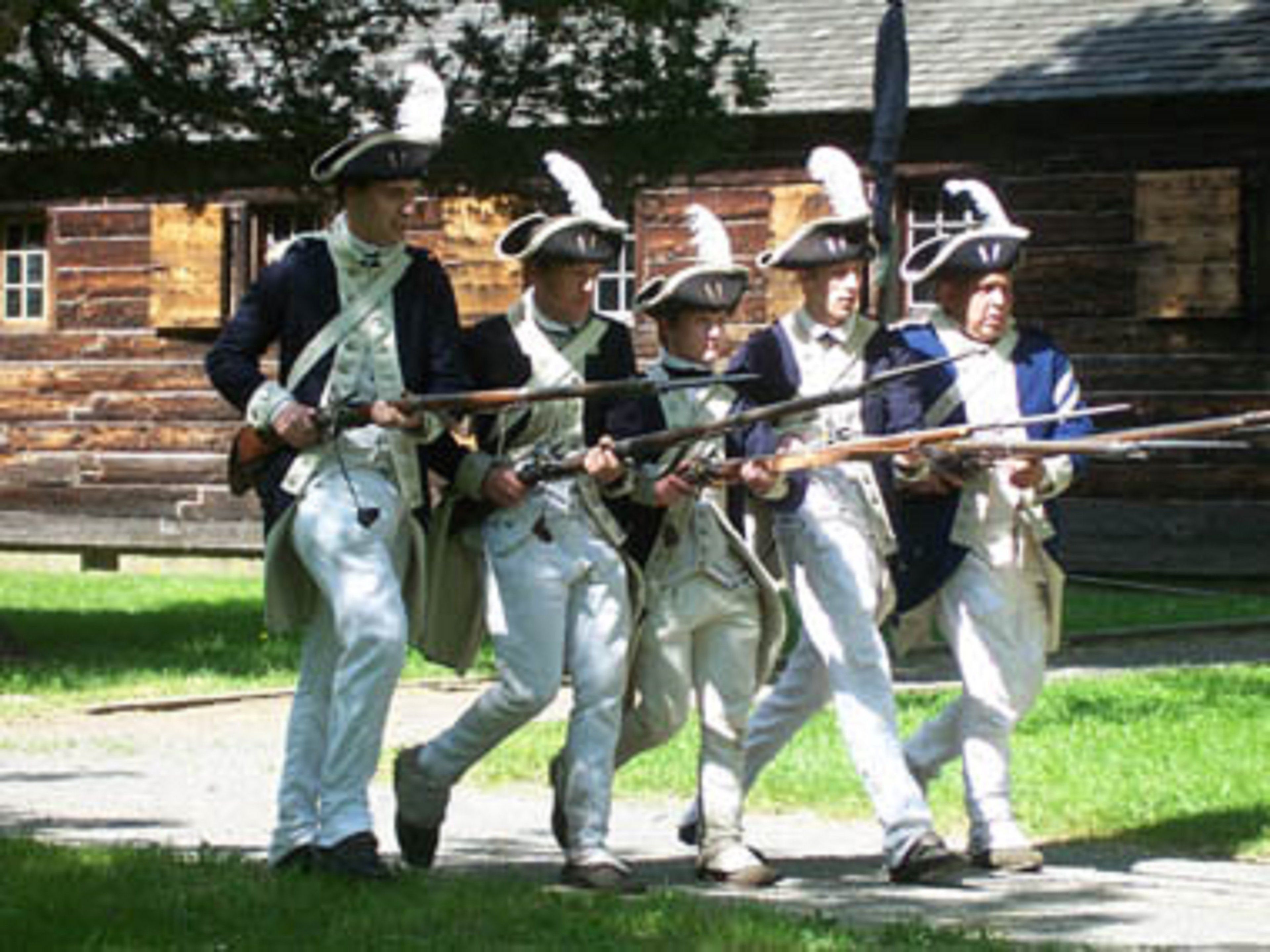 A group of people in historical military uniforms walking on a path.