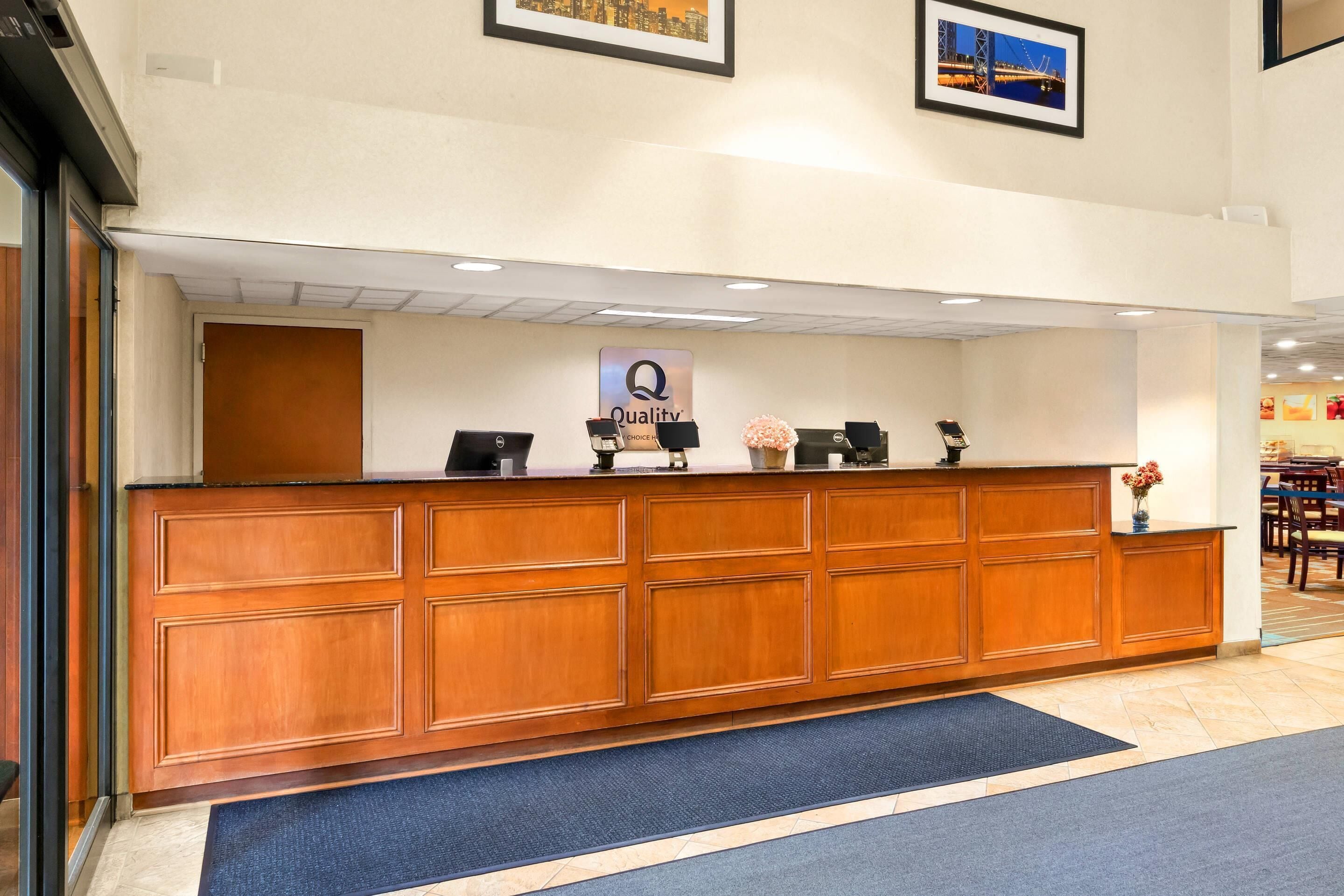 A reception desk with a 'Quality' sign, a wooden panel design, and a blue carpet.