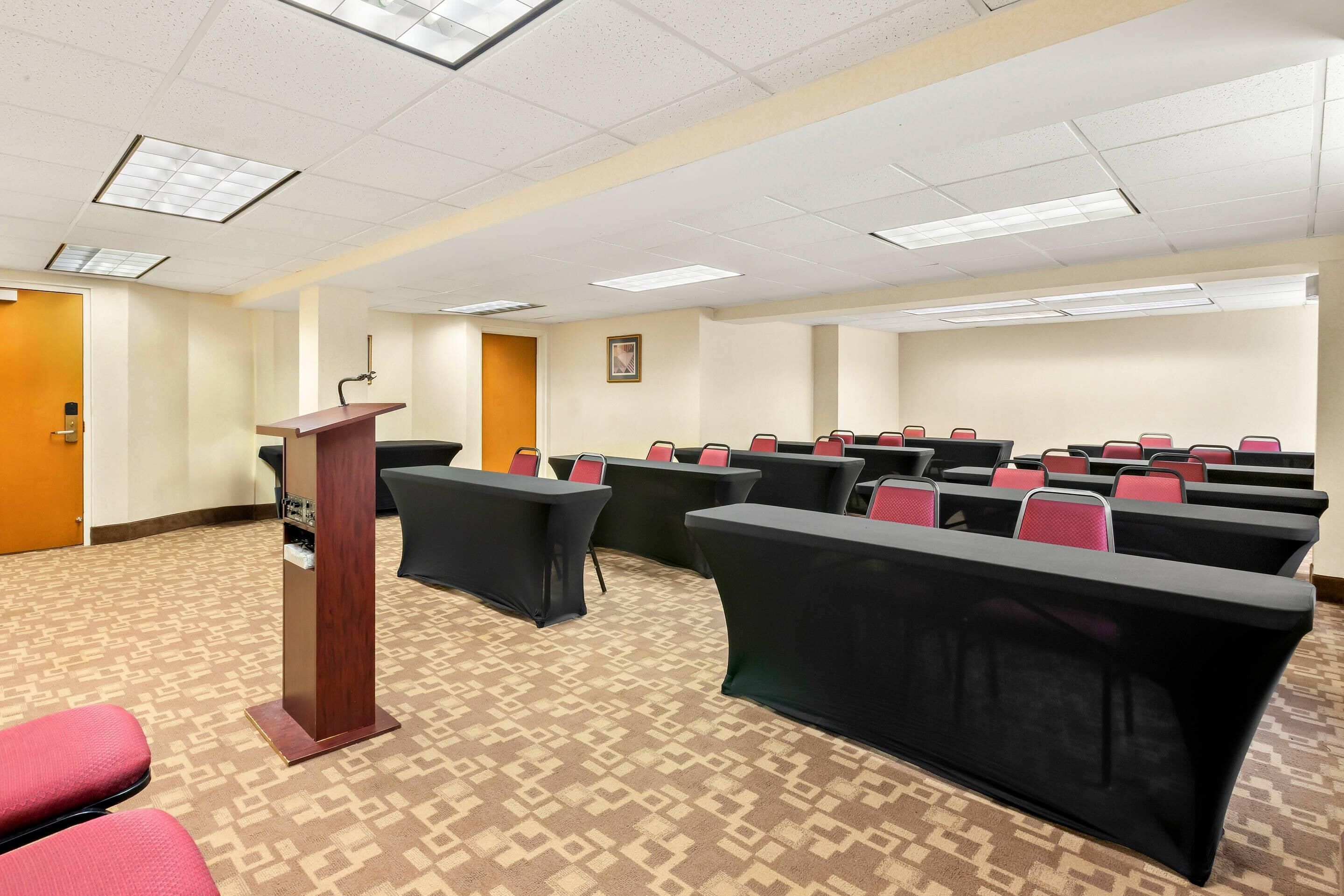 A conference room with a podium, rows of tables, and chairs.