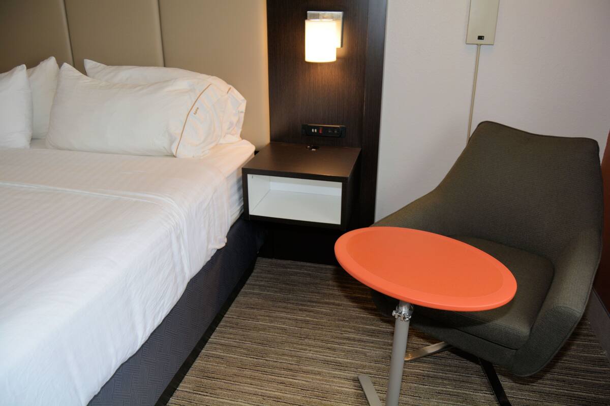 Ein Hotelzimmer mit Bett, Nachttisch, Tisch und Stuhl.