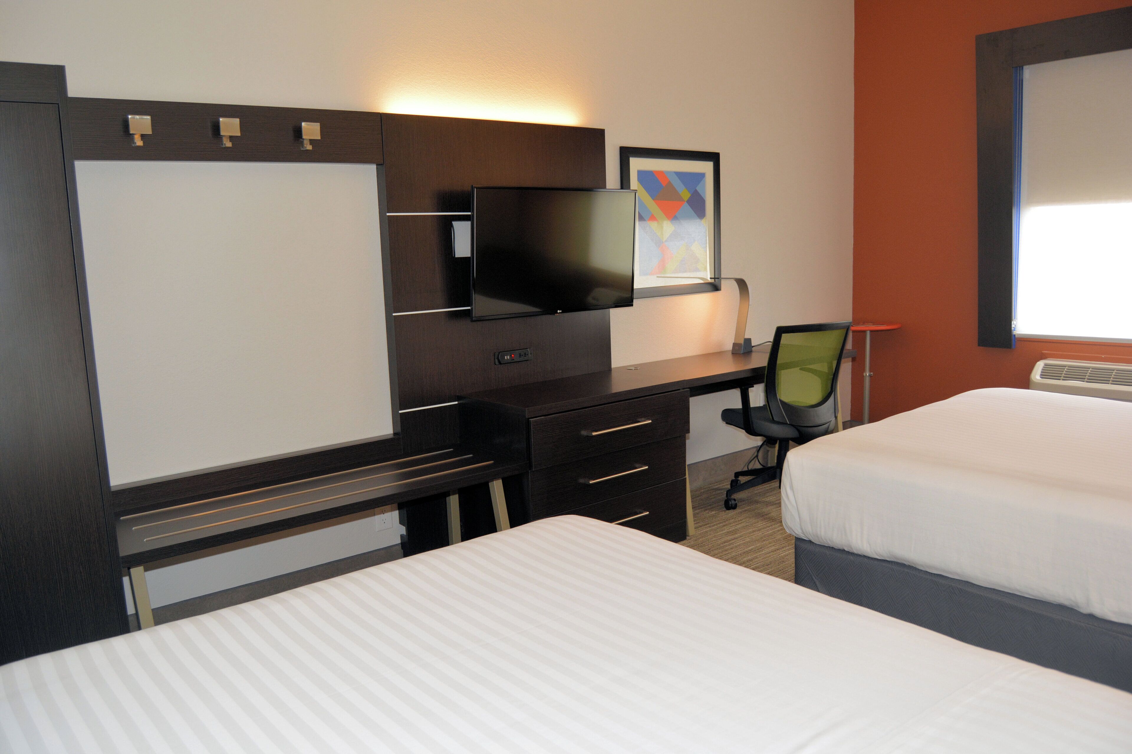 A hotel room with a bed, a desk with a computer, a television, and a window.