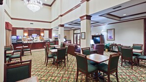Un vestíbulo de hotel con varias zonas de estar, una mesa de recepción y una araña.