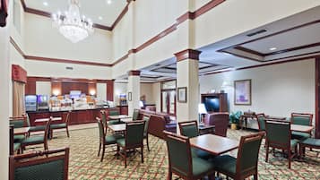A hotel lobby with multiple seating areas, a reception desk, and a chandelier.