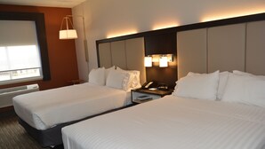 Una habitación de hotel con dos camas, una mesita de noche con teléfono y una lámpara de pared.