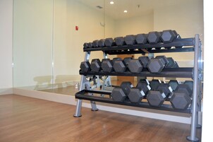 Un gimnasio con un estante de mancuernas y un espejo en la pared.