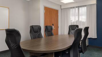 Una sala de conferencias con una mesa de madera y seis sillas negras.