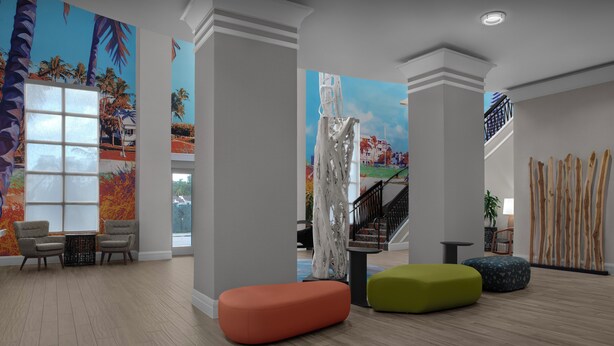 Un vestíbulo con un gran ventanal, dos sillones, una escalera y murales coloridos.