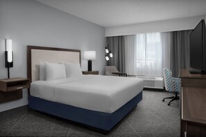 Een moderne hotelkamer met een groot bed, nachtkastjes, een bureau, een stoel en een televisie.