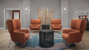 Una habitación con dos sillas naranjas, una mesa redonda negra y una escultura de madera decorativa.